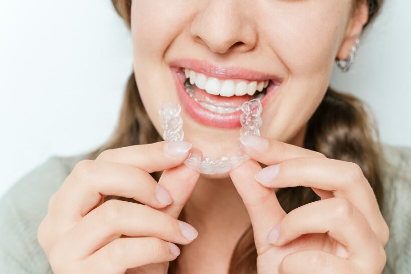 Woman smiling while holding a clear aligner
